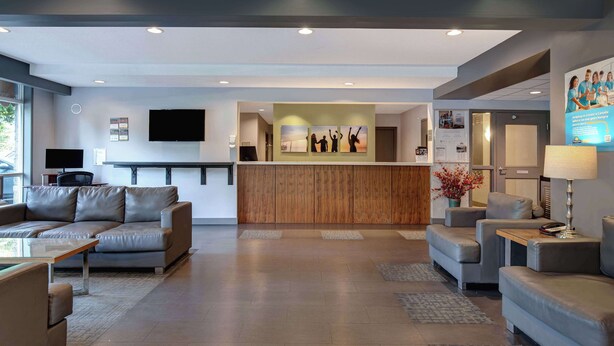 Een moderne hotellobby met een receptiebalie, leren banken en een flatscreen-televisie.