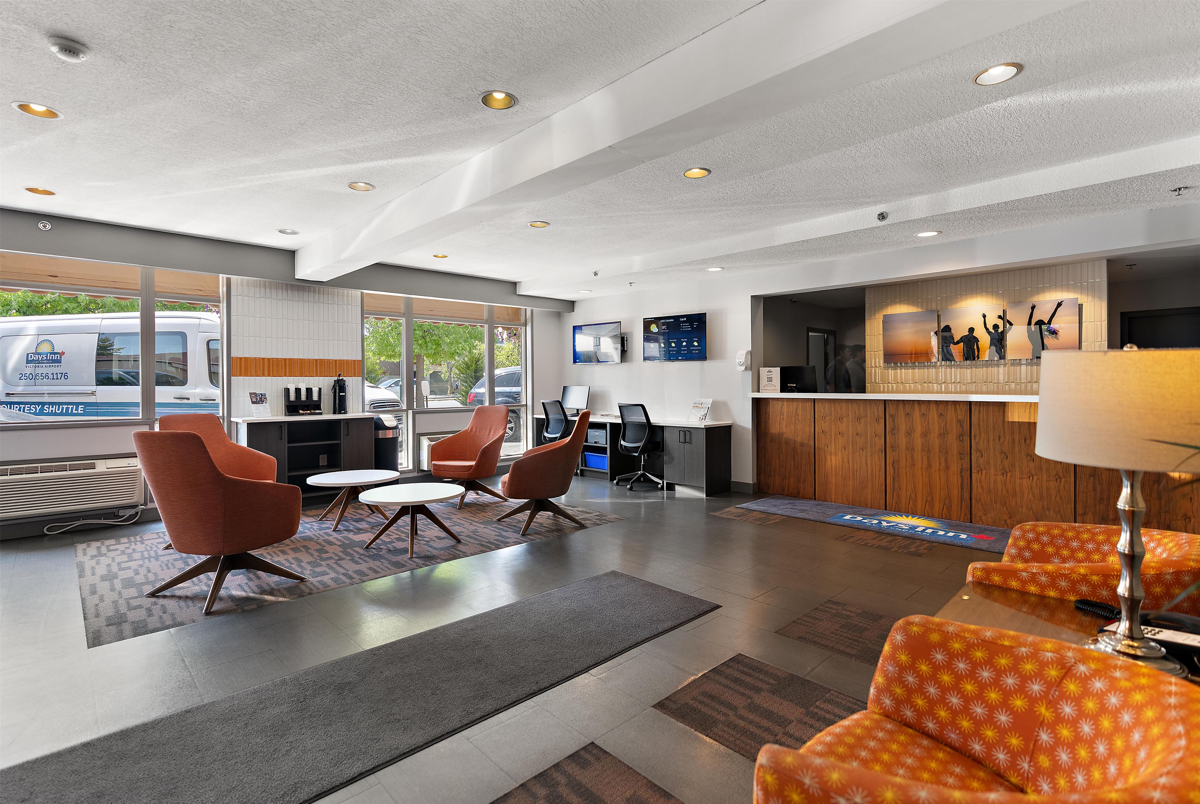 A modern hotel lobby with a reception desk, seating area, and large windows overlooking the street.