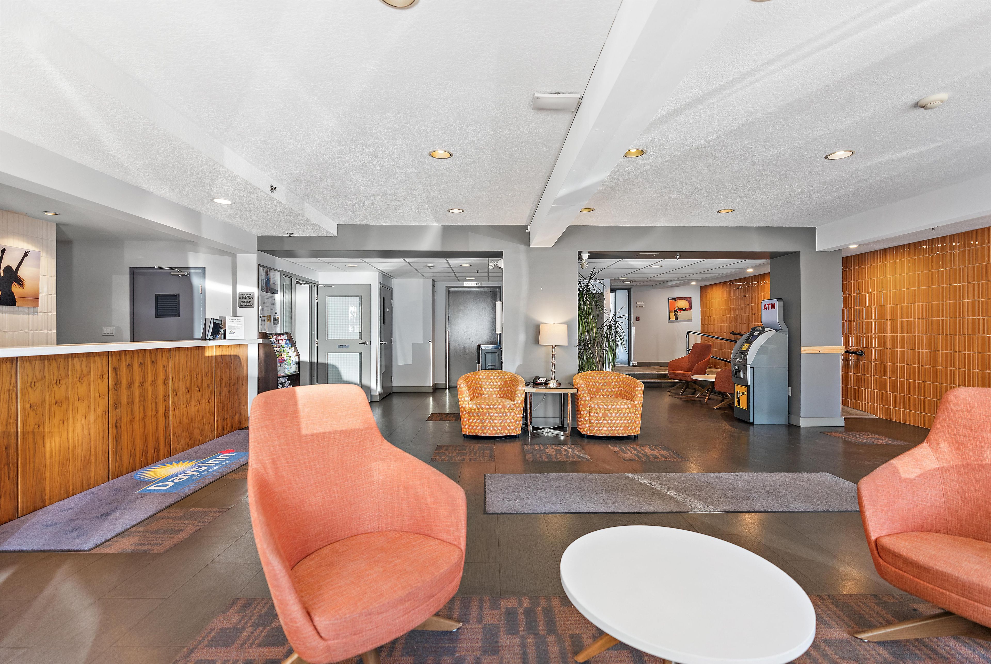 A modern lobby with a reception desk, seating area, and an ATM.