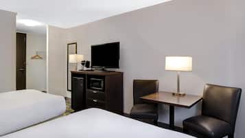Une chambre d’hôtel avec deux lits, un bureau avec une chaise, une télévision et un mini-bar.