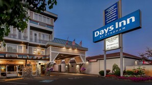 Een Days Inn by Wyndham gebouw met een bord, meerdere verdiepingen en een parkeerplaats.