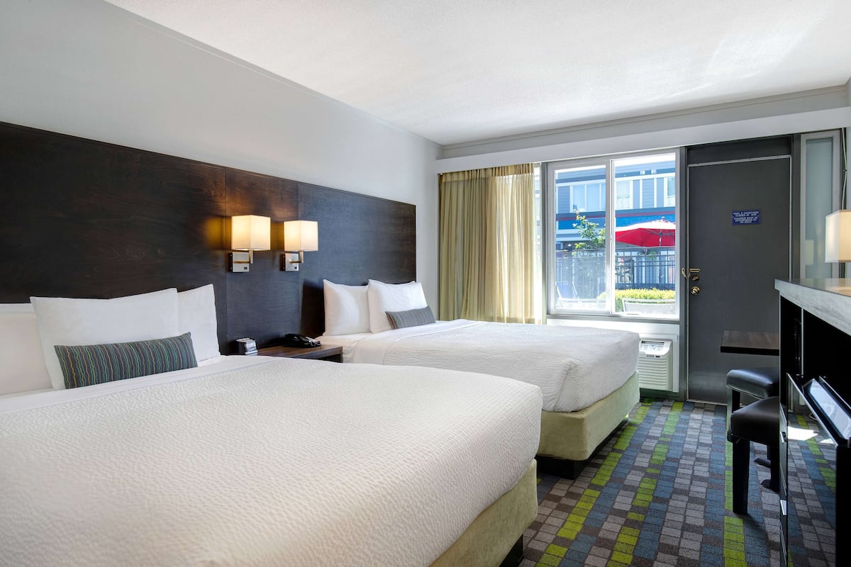 Ein Hotelzimmer mit zwei Betten, einem Schreibtisch und Blick ins Freie.