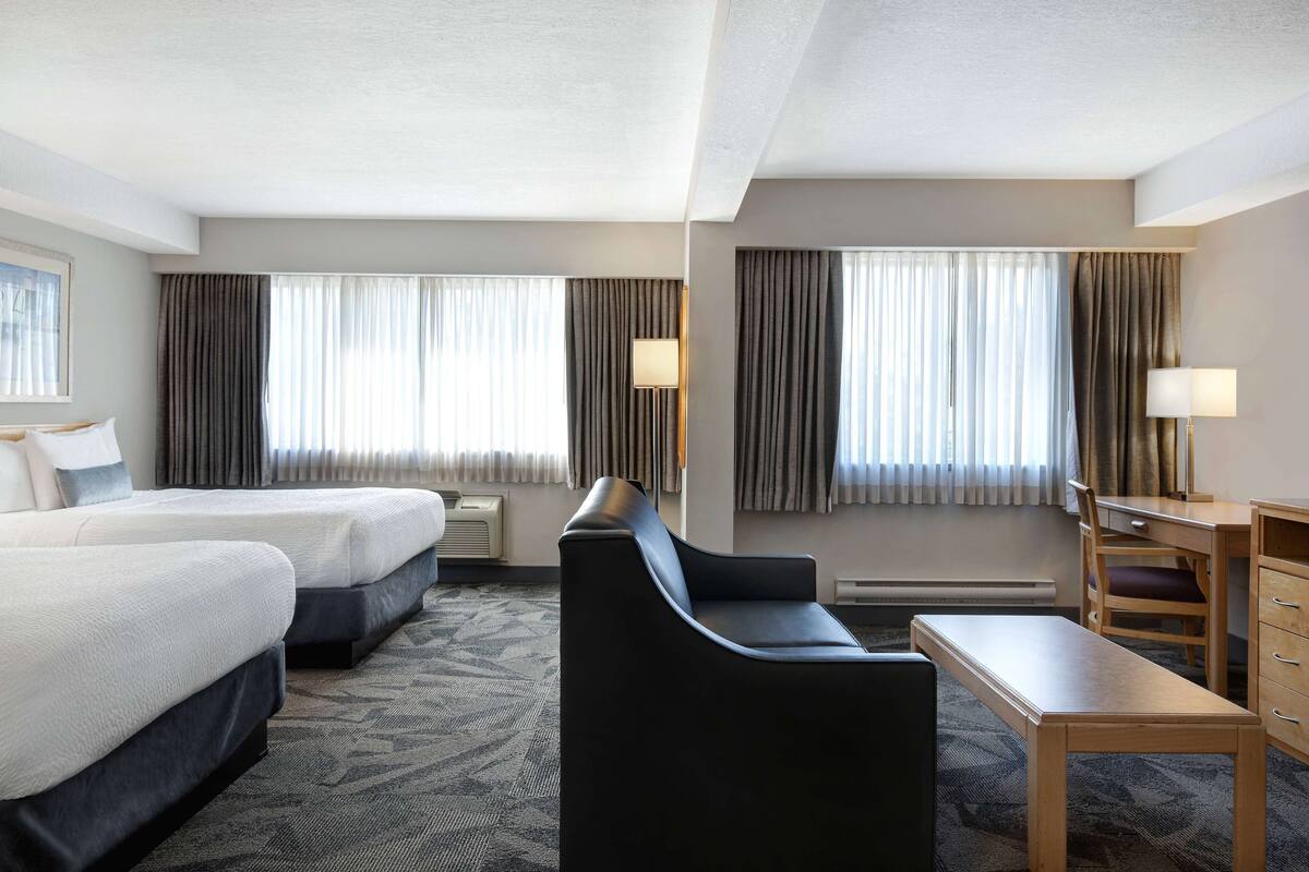 Une chambre d’hôtel avec deux lits, un bureau, une chaise et un canapé.