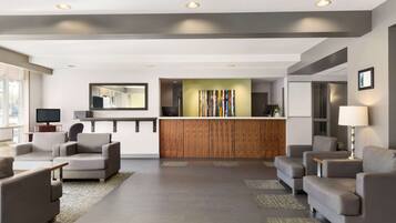 A modern lobby with a reception desk, sofas, and a large mirror.