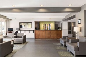 Un hall d’entrée moderne avec un comptoir d’accueil, des canapés et un grand miroir.