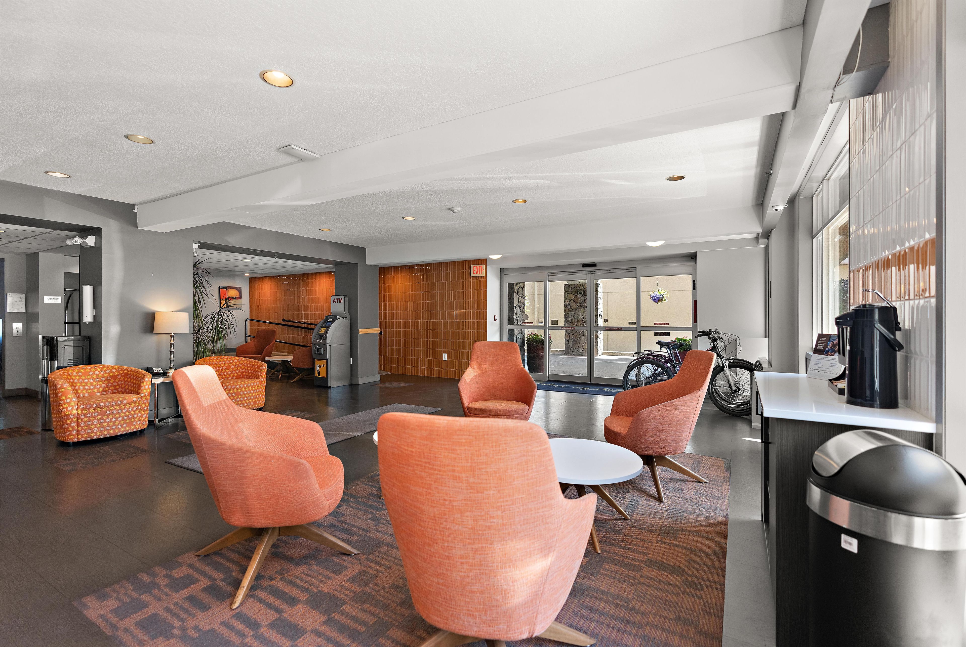 A modern lobby with seating, an ATM, and a view of the outside.
