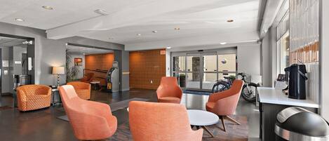 A modern lobby with seating, an ATM, and a view of the outside.