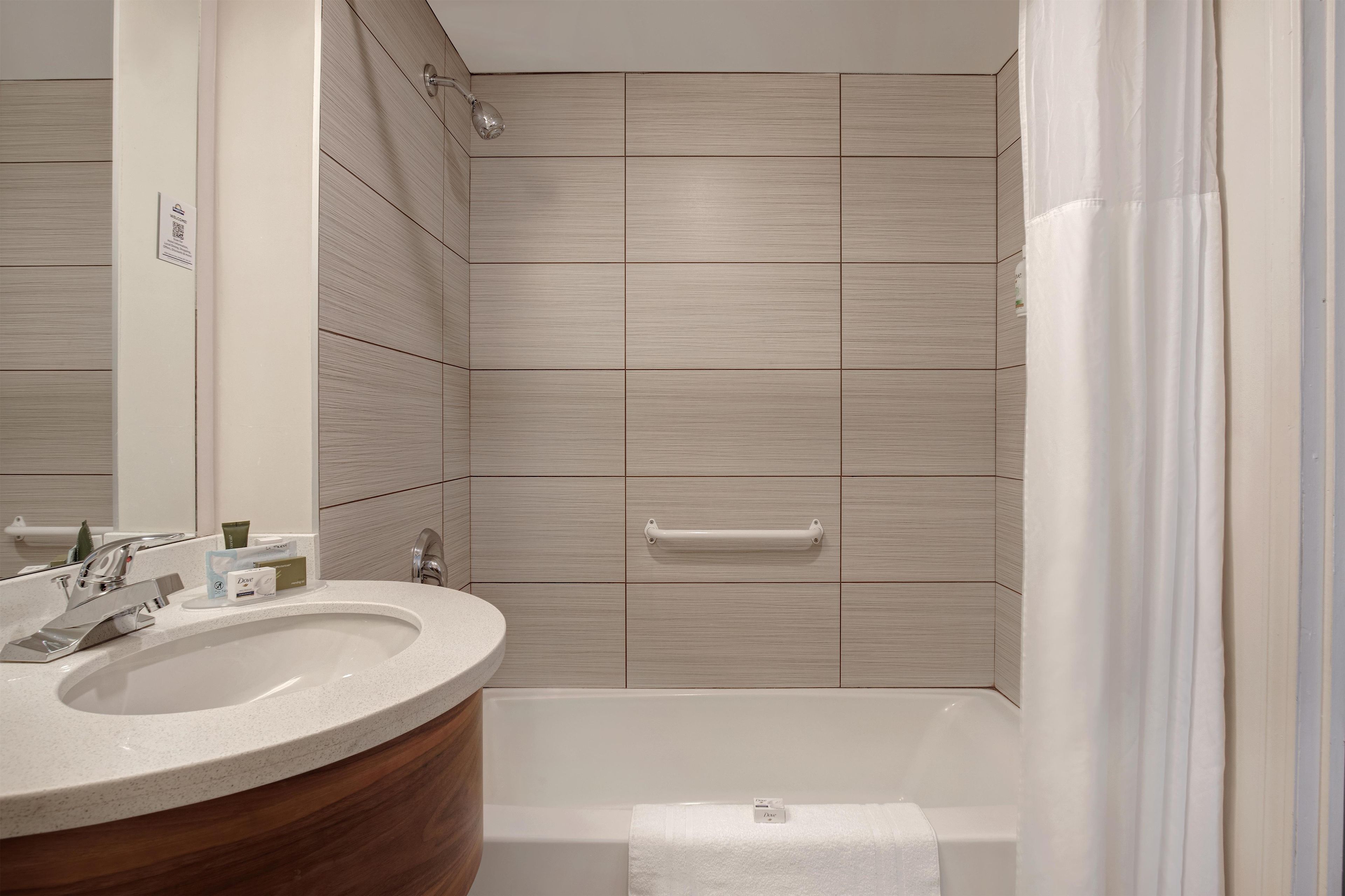 A modern bathroom with a freestanding bathtub, a vanity with a mirror, and a shower with a handheld showerhead.
