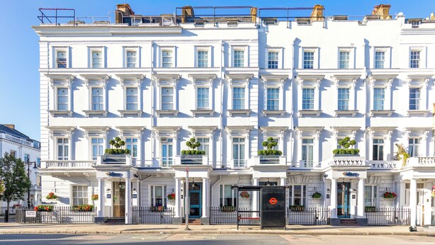 A row of white, multi-story buildings with uniform windows and a central entrance. - Sidney Hotel London Victoria  (London)