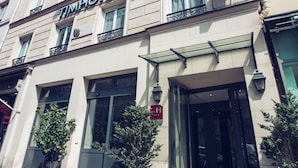 Ένα πολυώροφο ξενοδοχείο με κλασική πρόσοψη, μεγάλα παράθυρα και μια επιβλητική είσοδο.