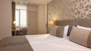 Una habitación de hotel con una cama grande, un escritorio con una computadora portátil y una silla.