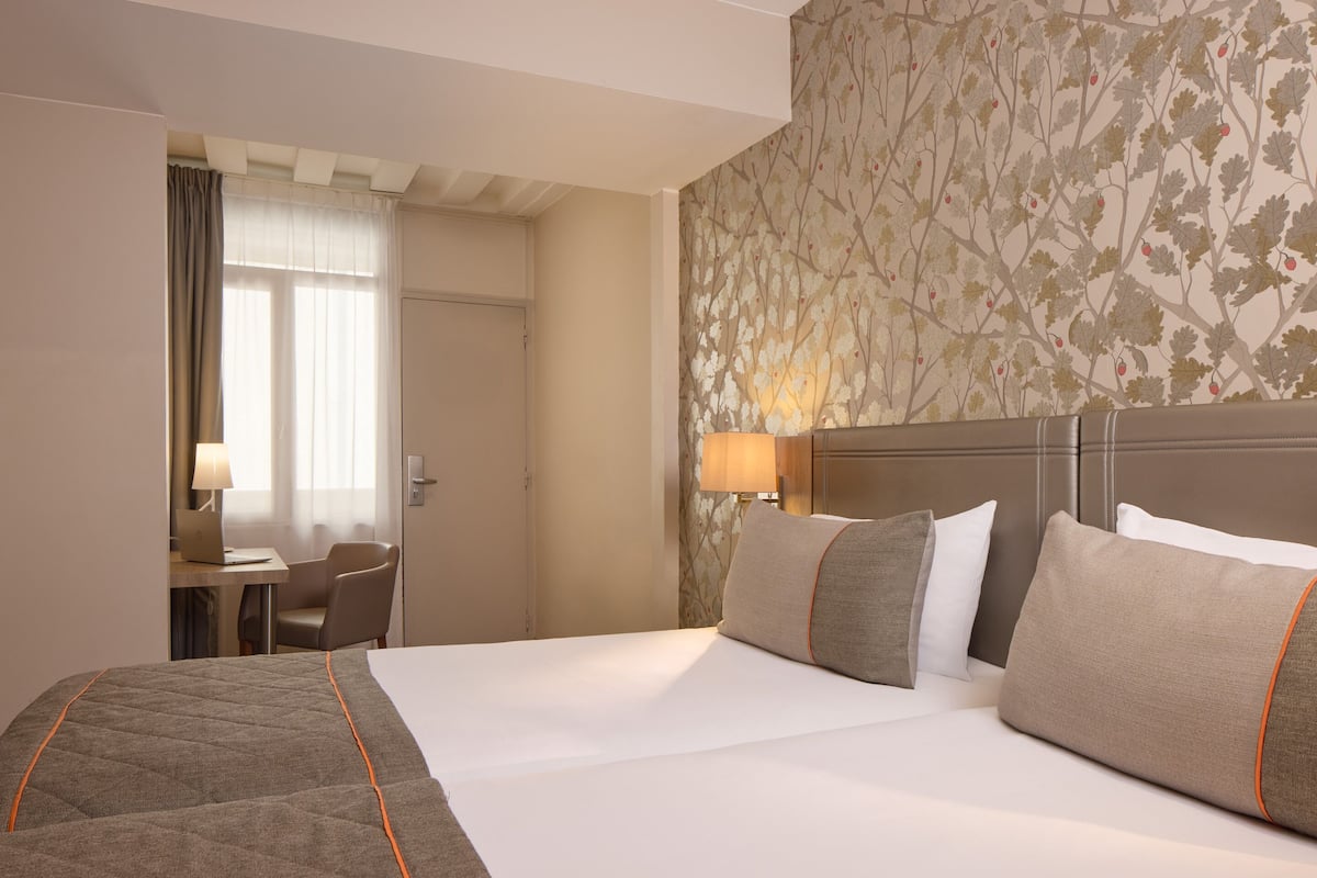 Hotellihuone, jossa on suuri sänky, työpöytä kannettavalla tietokoneella ja tuoli.