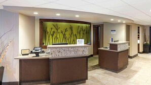 A reception area with two counters, a green wall with branch designs, and a tiled floor. - Best Western Plus New Ulm (New Ulm)
