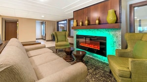 A modern living room with a fireplace, green armchairs, and a large sofa. - Best Western Plus New Ulm (New Ulm)