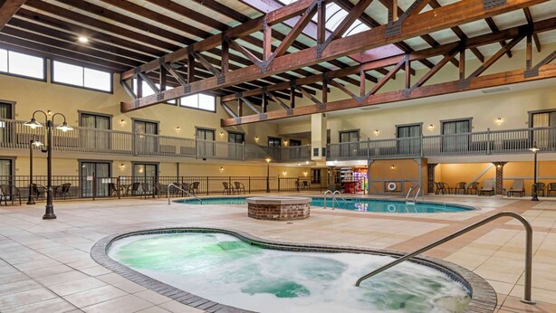 A spacious indoor pool area with multiple levels, a hot tub, and a seating area with tables and chairs. - Best Western Plus New Ulm (New Ulm)