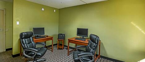 A conference room with two desks, two black leather chairs, a ceiling-mounted security camera, and a patterned carpet.