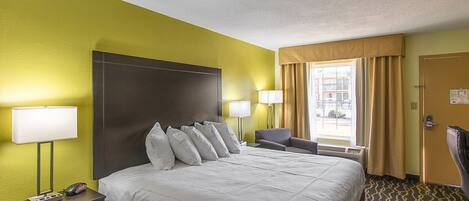A hotel room with a large bed, bedside lamps, a desk, and a chair.