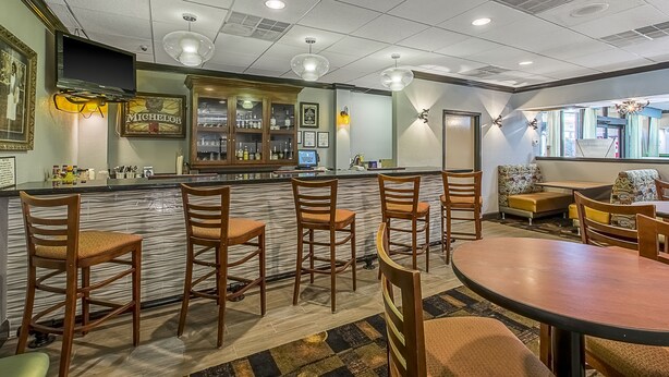 A bar area with wooden chairs, a counter with a computer, and a seating area with a sofa and chairs.