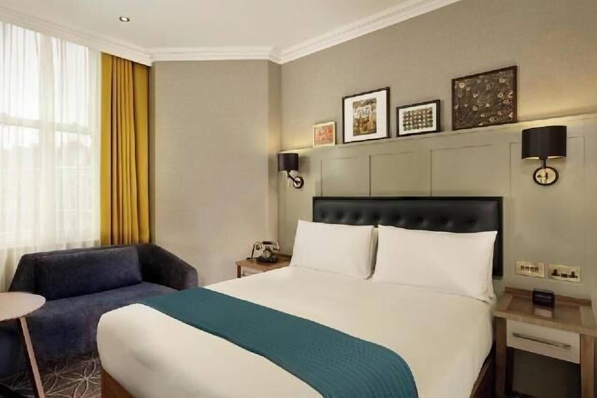 A hotel room with a bed, a sofa, a small table, and a nightstand.