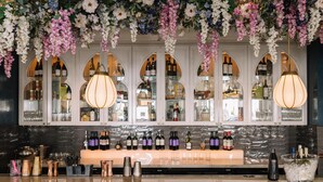 A bar area with a wine display, a bar counter, and hanging floral decorations. - 100 Queen's Gate Hotel London Kensington, Curio Collection by Hilton (London)