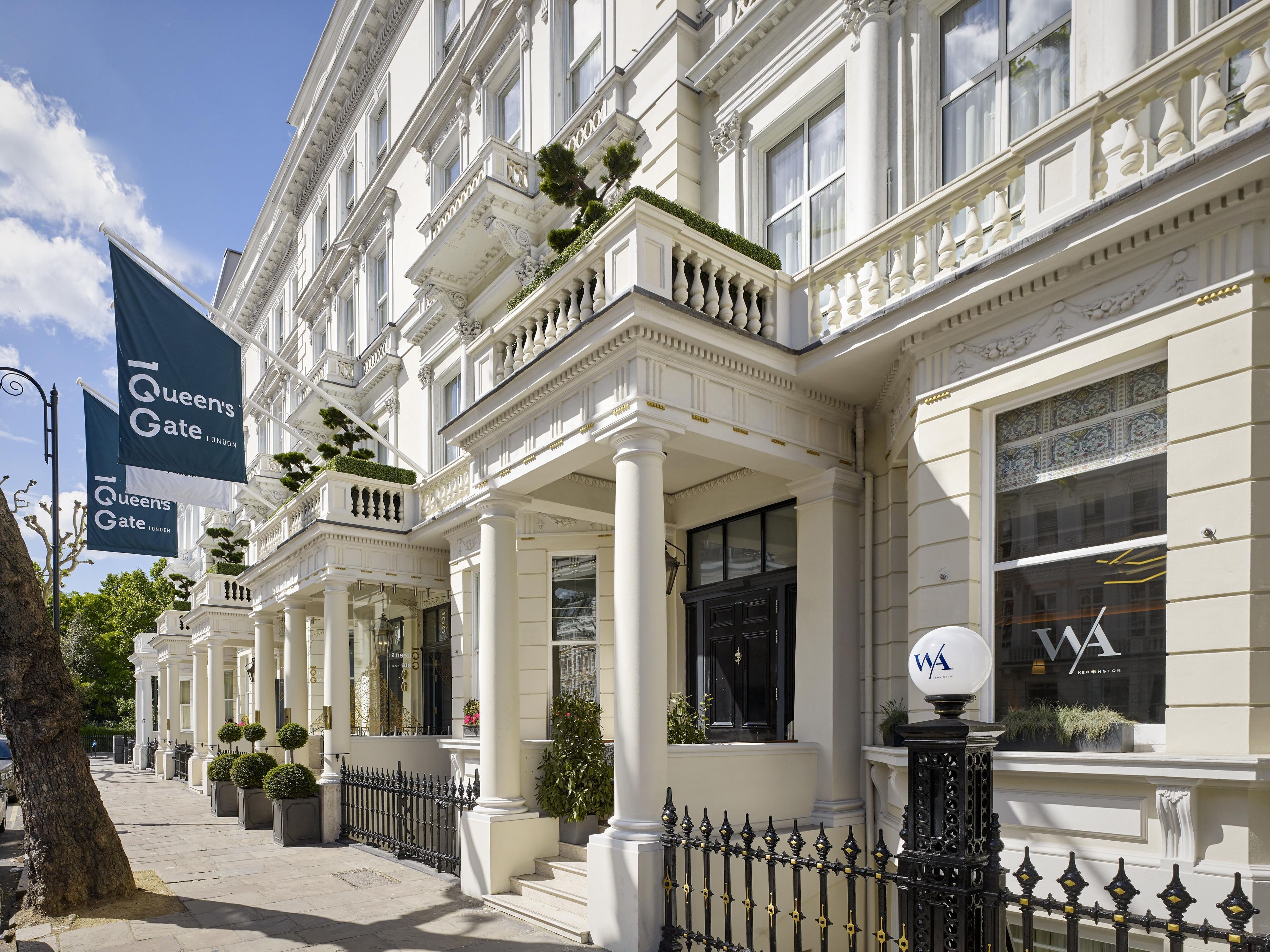 A row of Queen's Gate London buildings with classical architecture, large windows, and a black wrought iron fence.