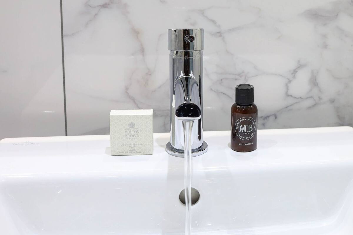 A bathroom sink with a modern faucet, a soap bar, and a body lotion bottle.