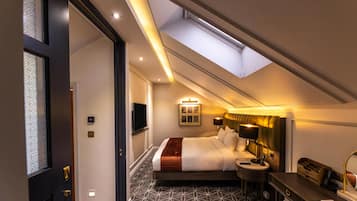 A hotel room with a skylight, a bed, bedside table, and a desk with a chair.