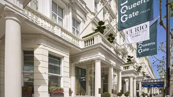 A classical building facade with columns, a balcony, and a sign for 'Queen's Gate London'.