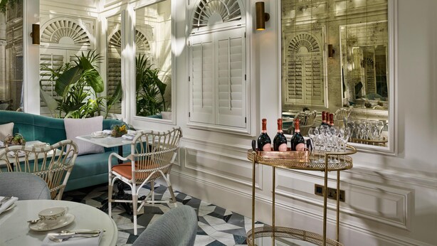 A room with a dining table, chairs, a sofa, and a bar area with bottles and glasses. - 100 Queen's Gate Hotel London Kensington, Curio Collection by Hilton (London)
