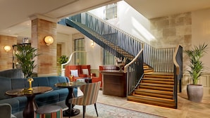 A spacious lobby with a modern staircase, plush seating, and a bar area. - 100 Queen's Gate Hotel London Kensington, Curio Collection by Hilton (London)