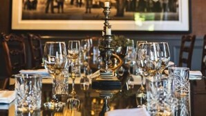 Une table à manger dressée, avec des verres à vin et un chandelier, et une photographie encadrée accrochée au mur derrière.