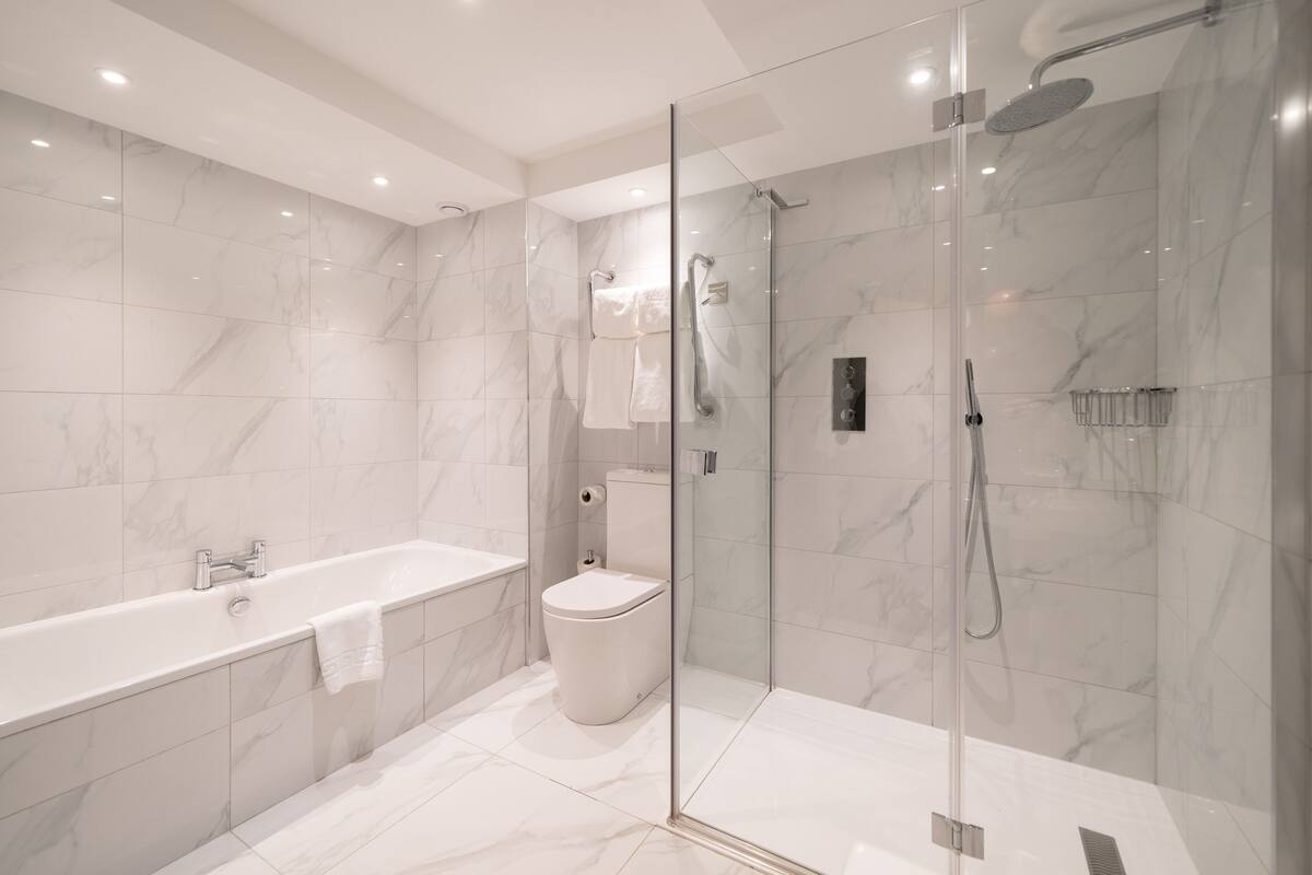 Ein modernes Badezimmer mit einer gläsernen Duschkabine, einer separaten Toilette und einer freistehenden Badewanne.
