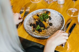 A dining table with a plate of food, cutlery, and a glass of wine.