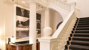 Una imponente escalera con alfombra de diseño blanco y negro, que conduce a un nivel superior con techo de cristal.