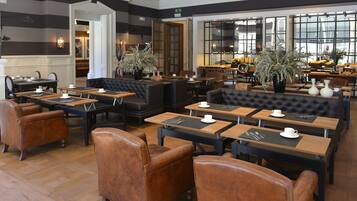 Un restaurant spacieux, doté de nombreuses tables et de banquettes, d’un plancher en bois et de grandes fenêtres offrant une vue sur la ville.