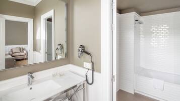 A modern bathroom with a large mirror, dual sinks, and a walk-in shower.