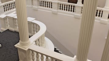 Una imponente escalera con barandillas y columnas blancas que conduce a un piso superior.