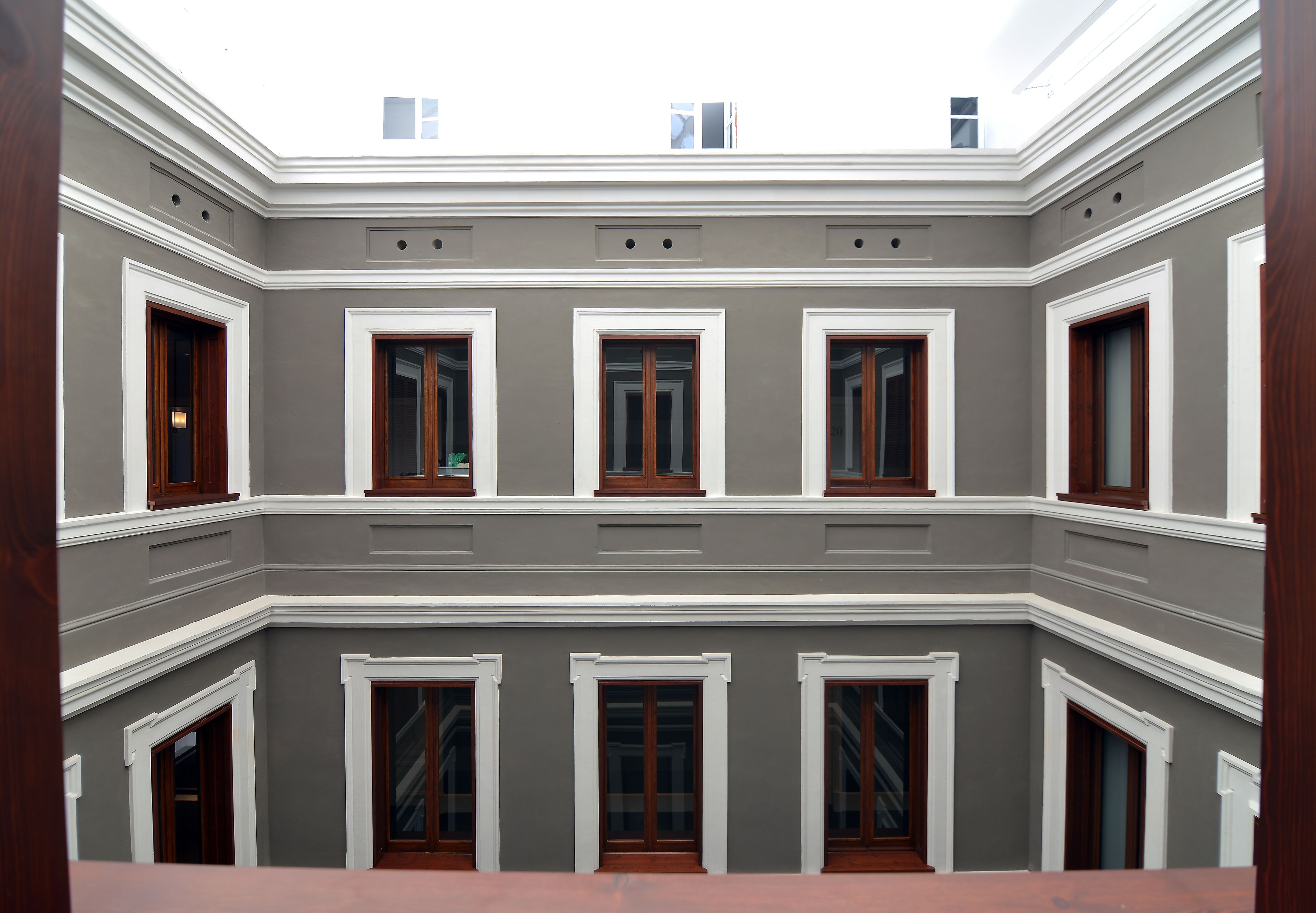 A building with a symmetrical facade, multiple windows, and a central skylight.