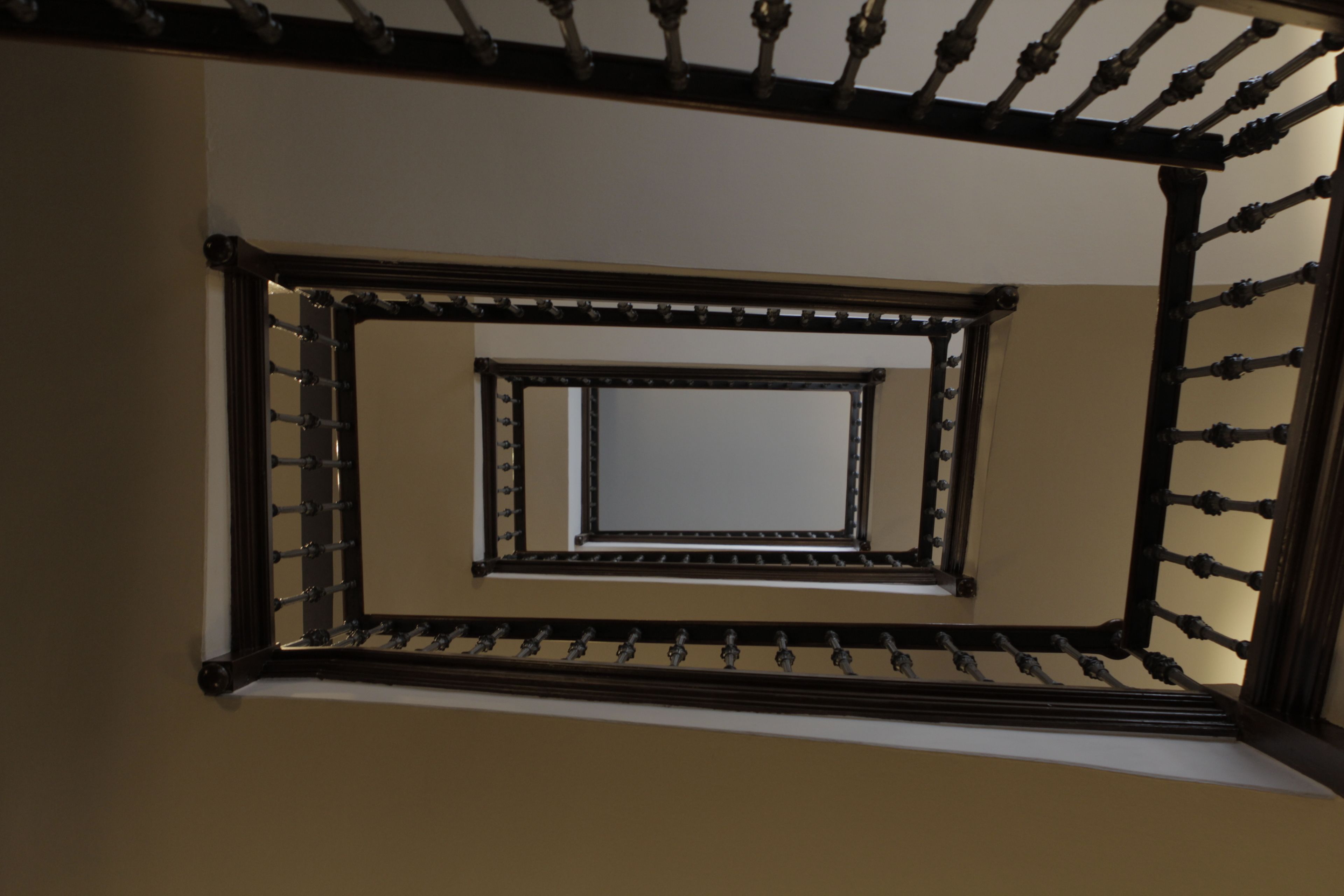 Una escalera de caracol con barandilla metálica y un ventanal rectangular en la parte superior.