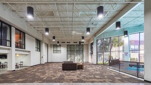 A spacious indoor area with a high ceiling, large windows, and a patterned carpet. - Red Roof Inn PLUS+ & Suites Houston - IAH Airport SW (Houston)