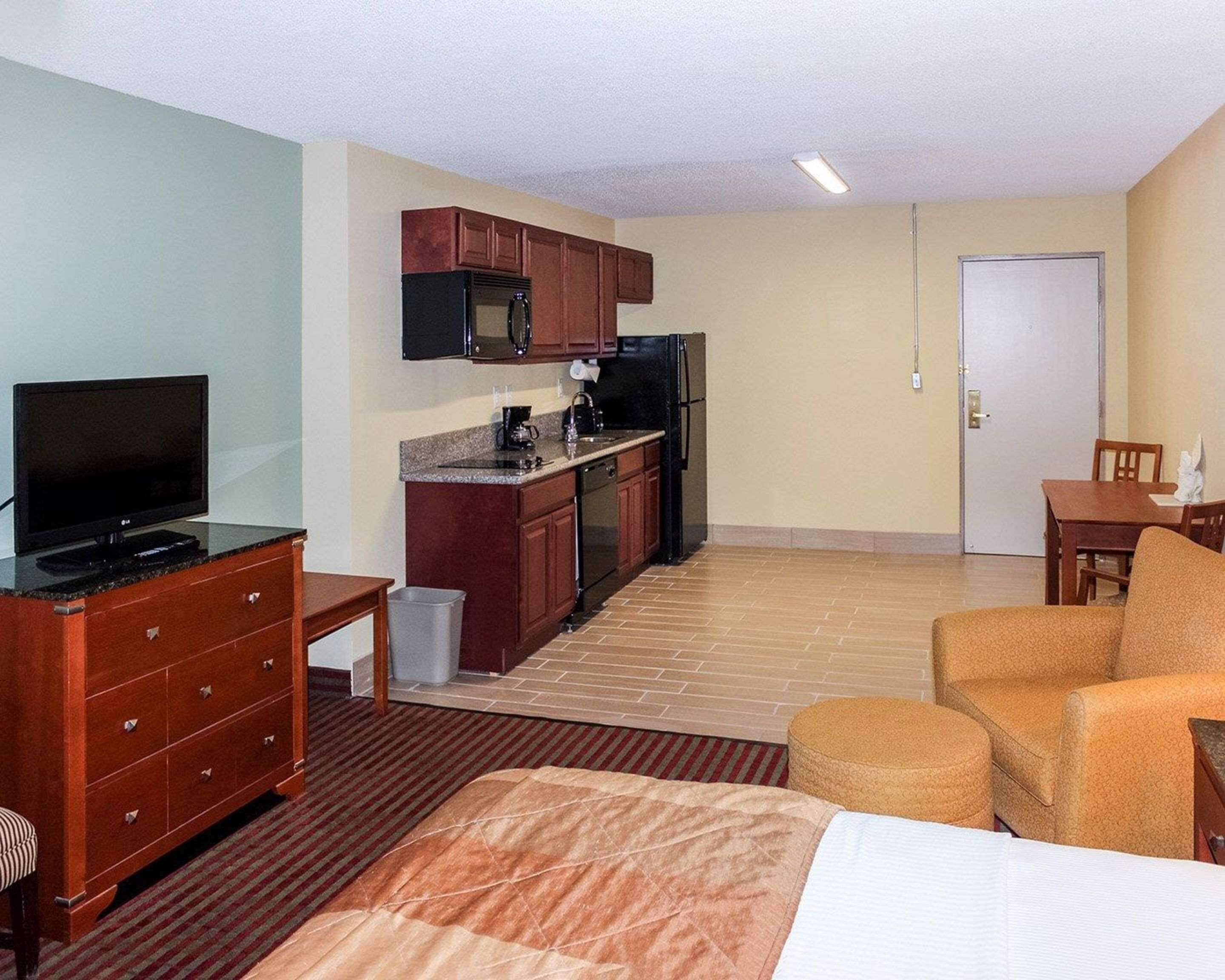 Une chambre d’hôtel équipée d’une kitchenette, d’une télévision, d’un lit, d’un canapé et d’une table à manger.