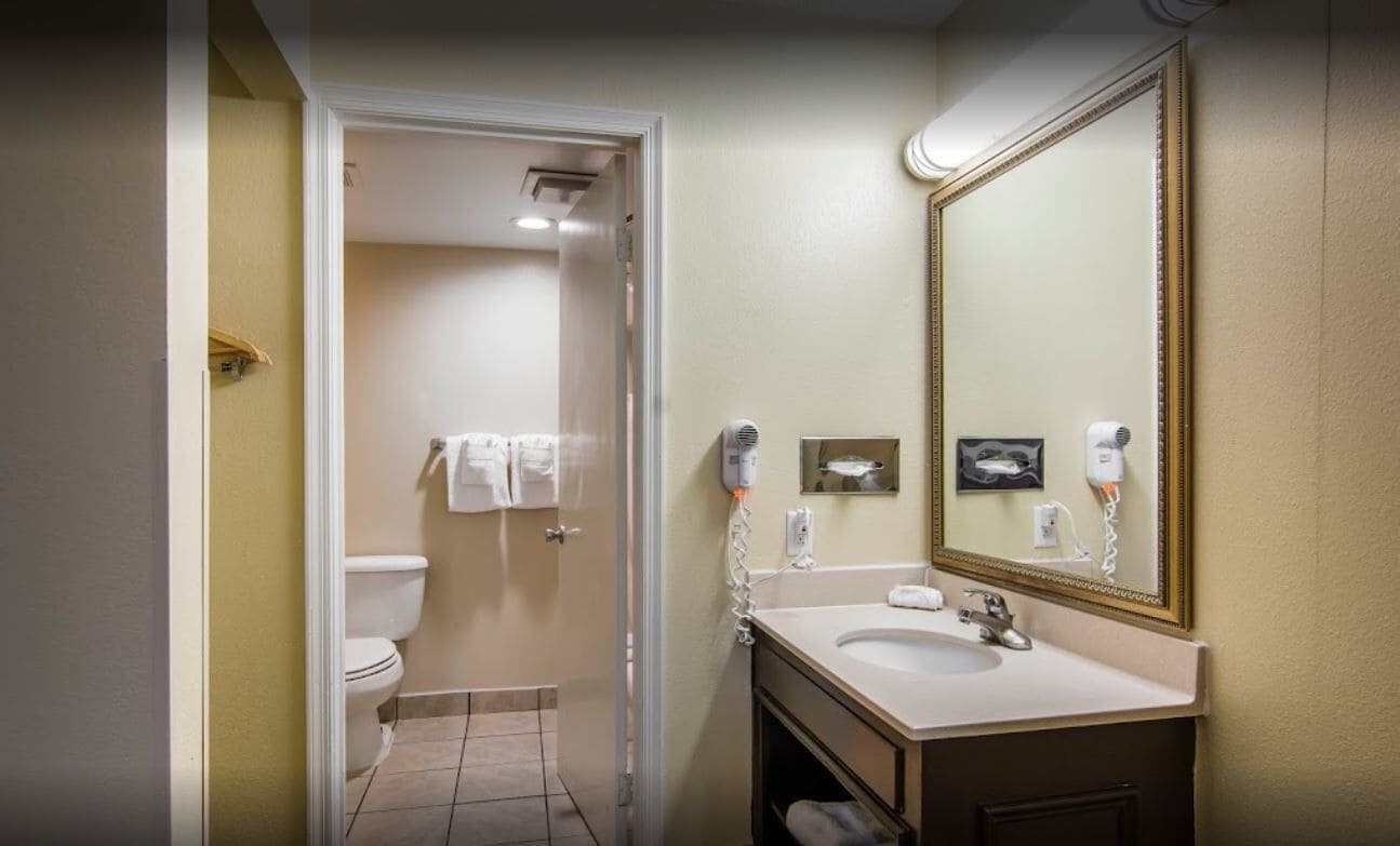 A bathroom with a toilet, sink, and mirror.