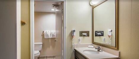 A bathroom with a toilet, sink, and mirror.