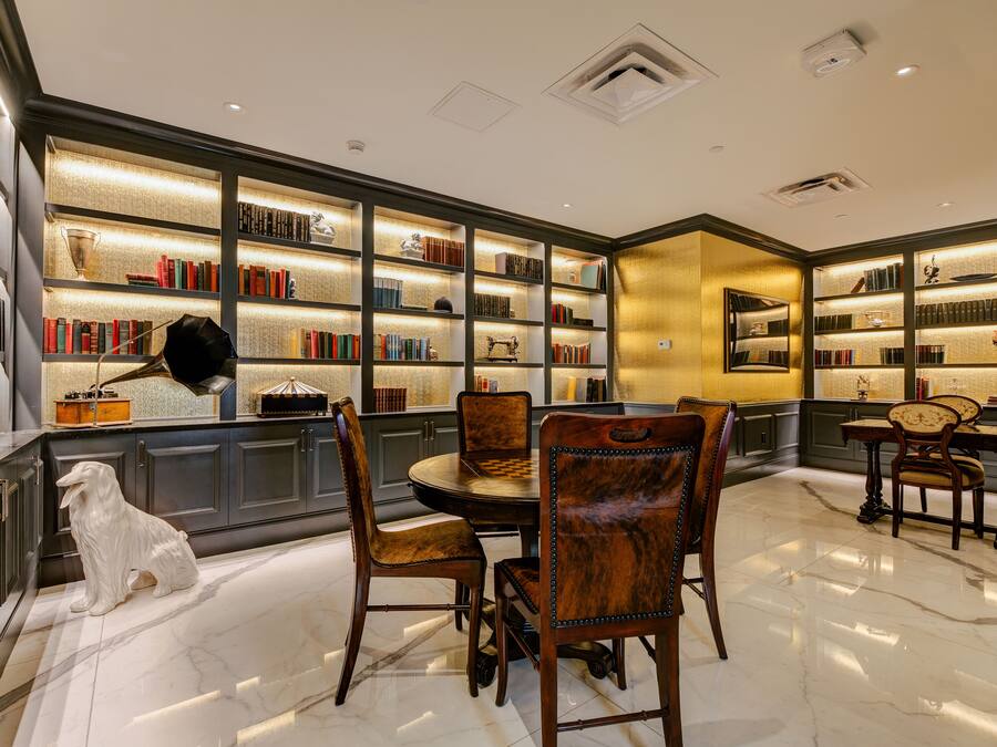 Uma biblioteca com estantes, uma mesa de xadrez e uma estátua de um cão branco.