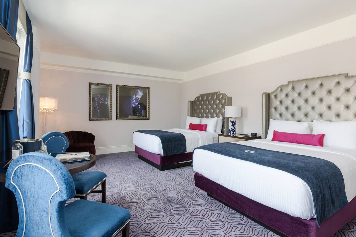 Ein Hotelzimmer mit zwei Betten, einem Schreibtisch mit Stuhl und einem großen Fenster.
