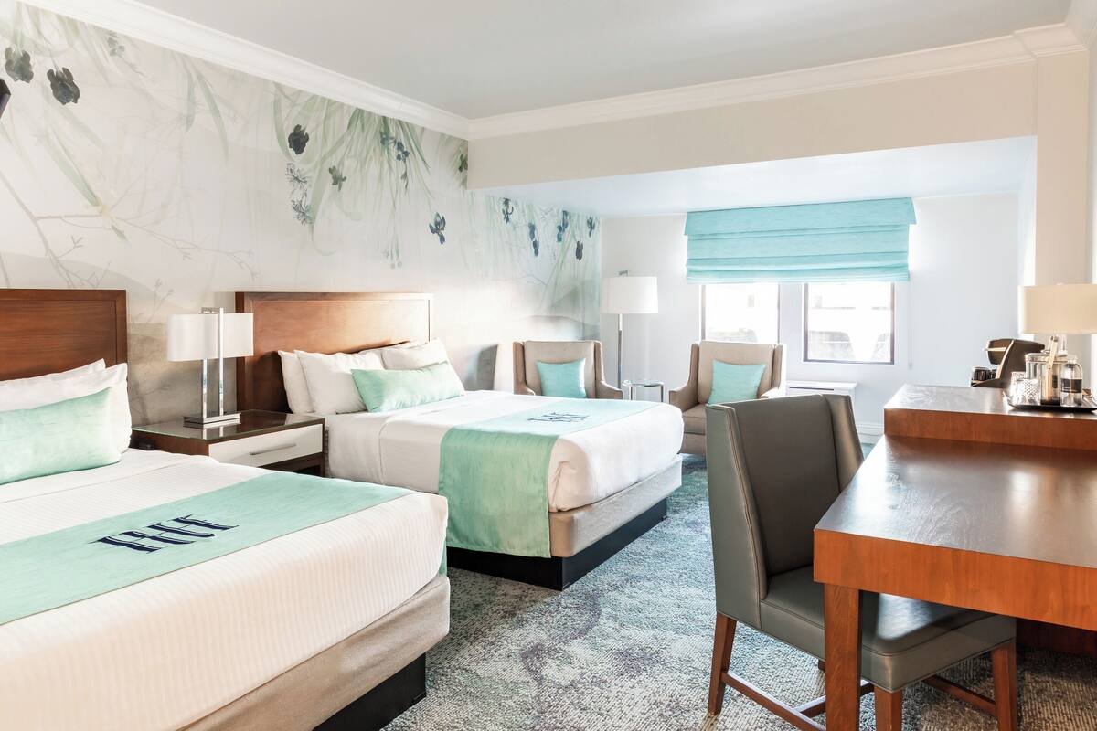 Ein Hotelzimmer mit zwei Betten, einem Schreibtisch und einem Stuhl.