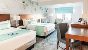 A hotel room with two beds, a desk, and a chair.