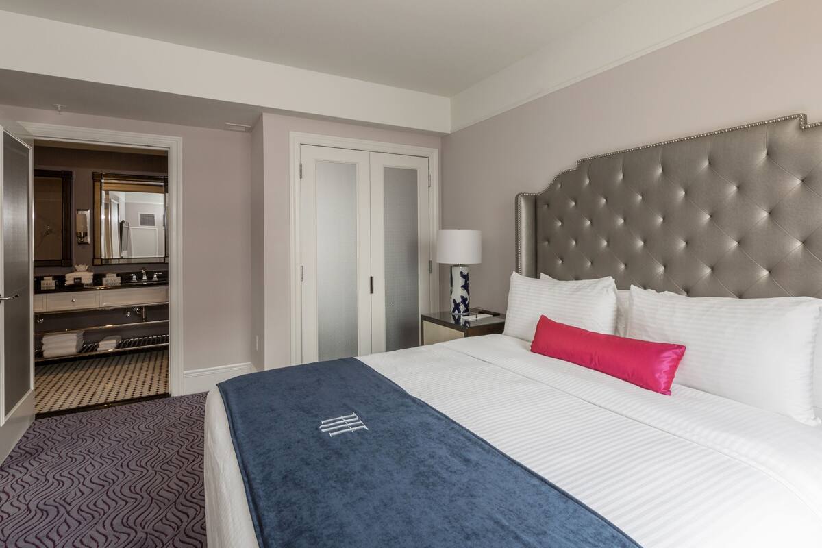 Ein Hotelzimmer mit einem großen Bett, einem Kopfteil, einem Kleiderschrank und einem Spiegel.