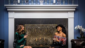 Two women seated in a room with a fireplace, a decorative screen, and a vase of flowers. - The Read House Hotel (Chattanooga)