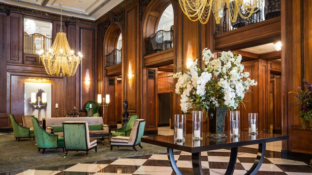A lobby with a checkered floor, a central table with vases, and green upholstered chairs. - The Read House Hotel (Chattanooga)